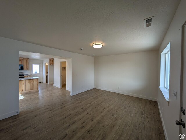 340 N 2650 W Unit 16, Tremonton, UT 84337 - unfurnished living room featuring visible vents, baseboards, wood finished floors, and a textured ceiling