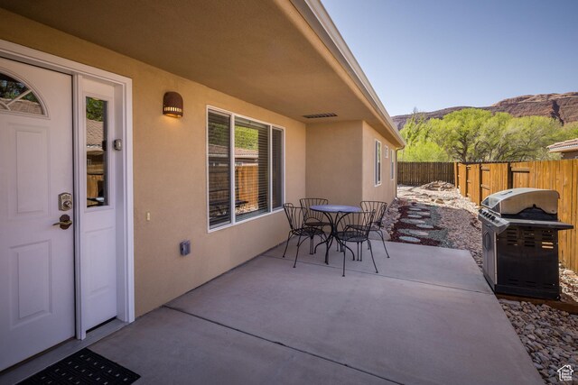 view of patio with a mountain view, outdoor dining area, a grill, and fence