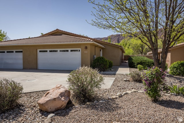 327 W Williams Way, Moab, UT 84532 - view of front of home with stucco siding, an attached garage, driveway, and a tile roof