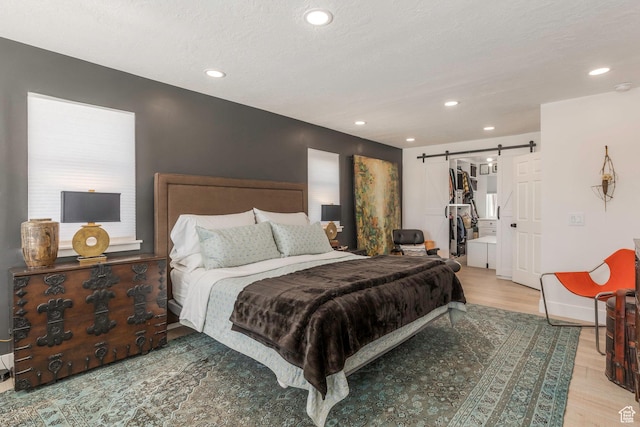 528 W Weber Canyon Rd, Oakley, UT 84055 - bedroom featuring a barn door, light wood-style flooring, recessed lighting, and a spacious closet