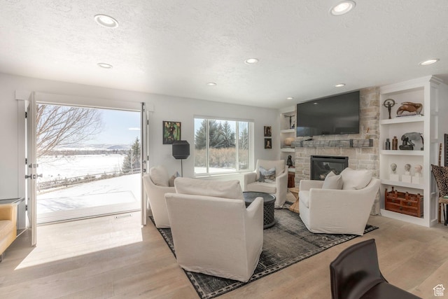 528 W Weber Canyon Rd, Oakley, UT 84055 - living area featuring recessed lighting, a textured ceiling, a stone fireplace, light wood-style flooring, and built in features