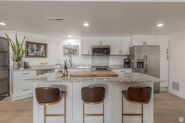 528 W Weber Canyon Rd, Oakley, UT 84055 - kitchen with appliances with stainless steel finishes, a kitchen bar, white cabinetry, recessed lighting, and a center island