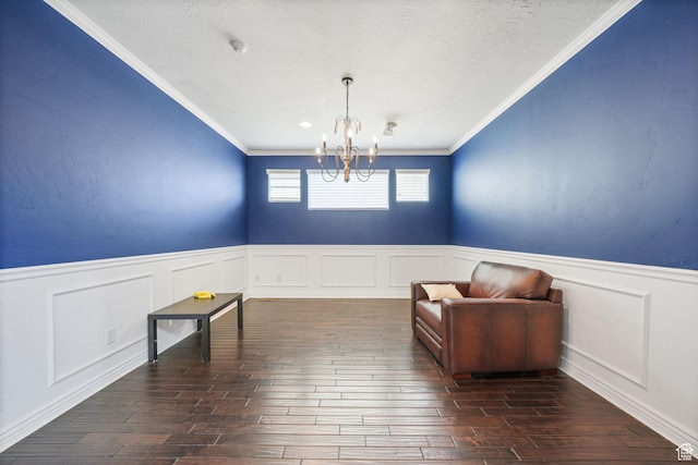 unfurnished room featuring dark wood-style floors, wainscoting, a notable chandelier, and ornamental molding