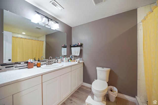 bathroom featuring vanity, visible vents, toilet, and wood finished floors