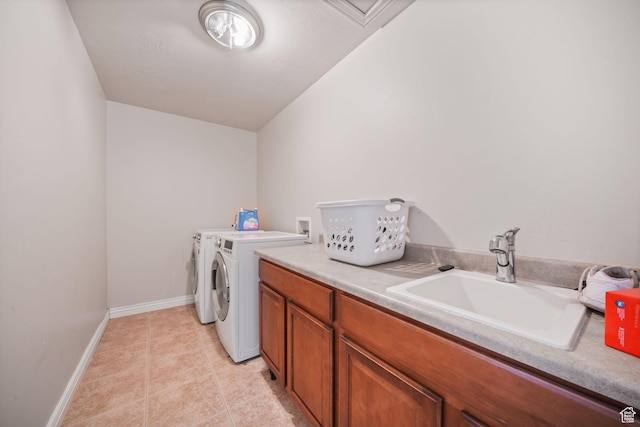 clothes washing area featuring baseboards, a sink, cabinet space, washing machine and clothes dryer, and light tile patterned flooring