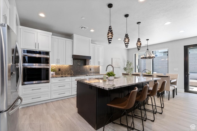 5266 W 2480 S Unit 149, Hurricane, UT 84737 - kitchen with backsplash, light stone countertops, a kitchen island with sink, appliances with stainless steel finishes, and a sink