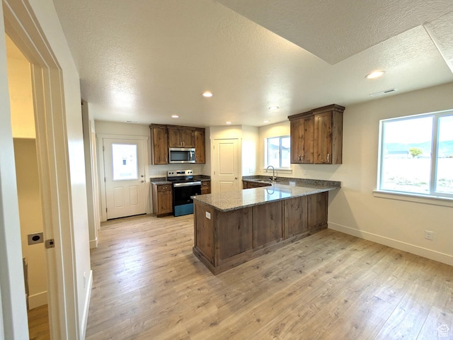 kitchen featuring a peninsula, visible vents, stainless steel microwave, a sink, and electric stove