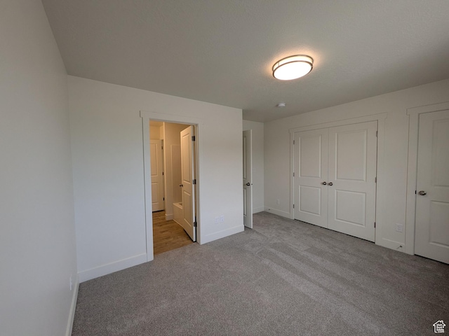 unfurnished bedroom featuring ensuite bathroom, baseboards, and carpet