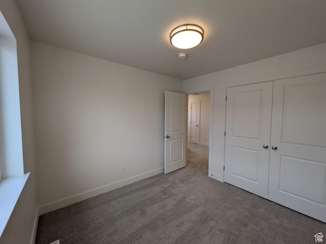 unfurnished bedroom with a closet, baseboards, and carpet flooring