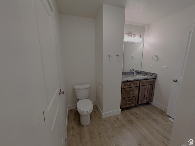 bathroom with vanity, baseboards, toilet, and wood finished floors