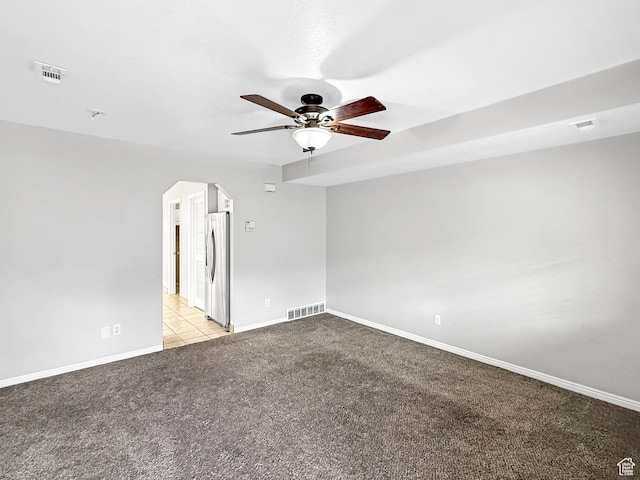 unfurnished room with baseboards, visible vents, ceiling fan, arched walkways, and light colored carpet