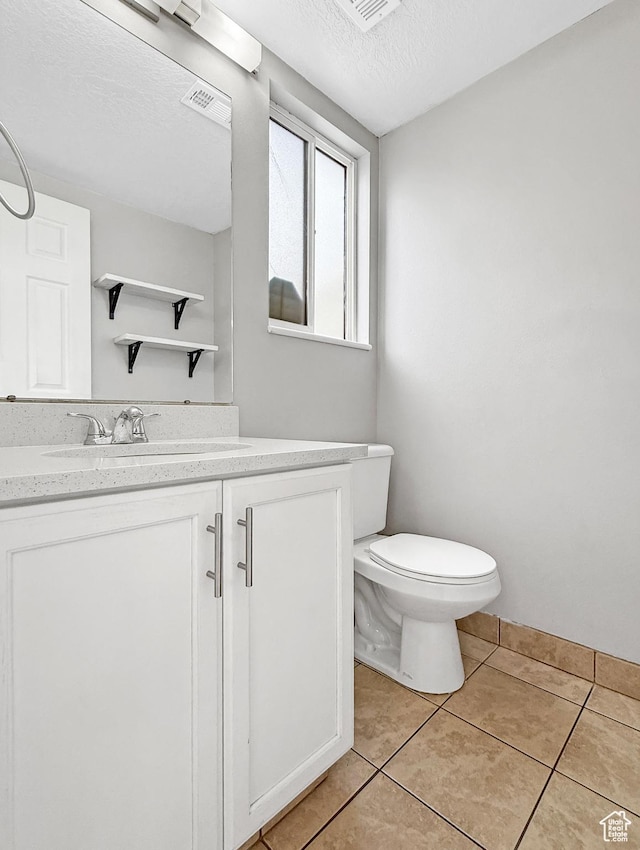 bathroom with vanity, tile patterned flooring, a textured ceiling, toilet, and visible vents