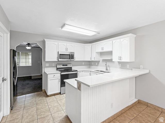 kitchen with a peninsula, light tile patterned flooring, ceiling fan, stainless steel appliances, and a sink