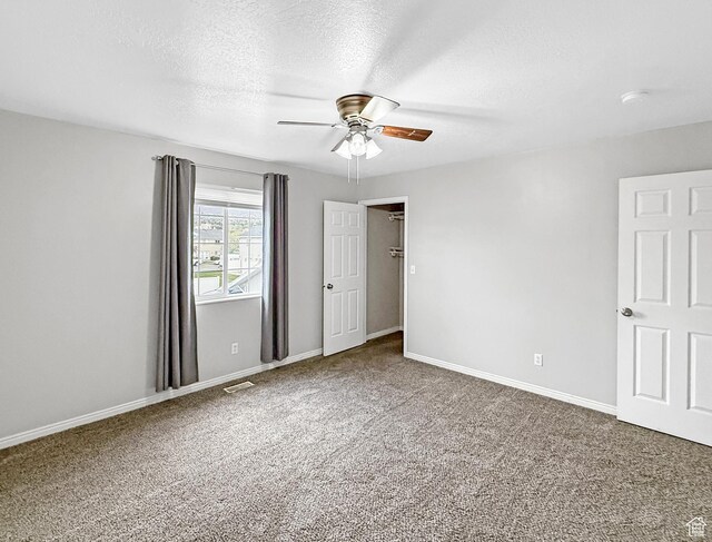 spare room with ceiling fan, carpet flooring, baseboards, and a textured ceiling