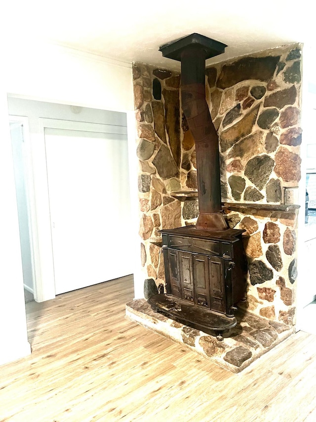 room details with a wood stove, ornamental molding, and wood finished floors