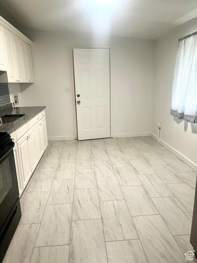 kitchen with marble finish floor, baseboards, white cabinetry, and black range with electric cooktop