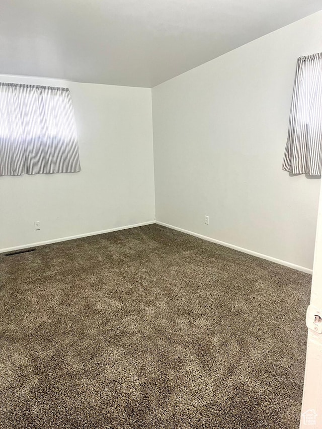 empty room featuring dark carpet and baseboards