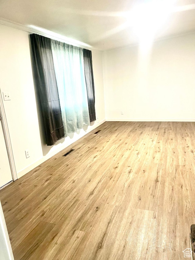 unfurnished room featuring visible vents, baseboards, and wood finished floors