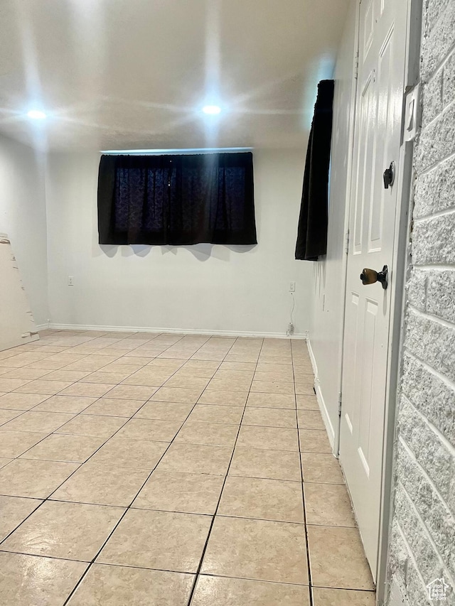spare room featuring light tile patterned floors and baseboards