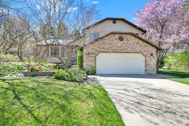 view of front of home featuring a front yard, an attached garage, brick siding, and concrete driveway