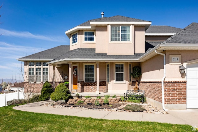2115 N 5 E, Layton, UT 84041 - view of front of home with stucco siding, brick siding, covered porch, fence, and a shingled roof