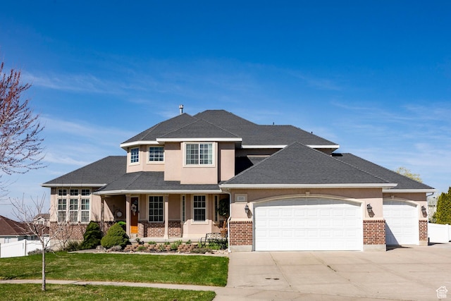 2115 N 5 E, Layton, UT 84041 - view of front facade featuring a garage, stucco siding, driveway, covered porch, and brick siding