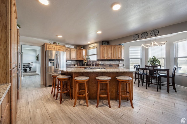 2115 N 5 E, Layton, UT 84041 - kitchen with stainless steel fridge with ice dispenser, wood tiled floors, decorative backsplash, a kitchen breakfast bar, and recessed lighting