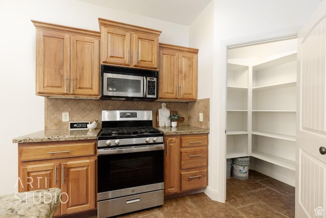 1971 S Great Basin Dr, Washington, UT 84780 - kitchen with appliances with stainless steel finishes, decorative backsplash, light stone counters, and dark tile patterned flooring
