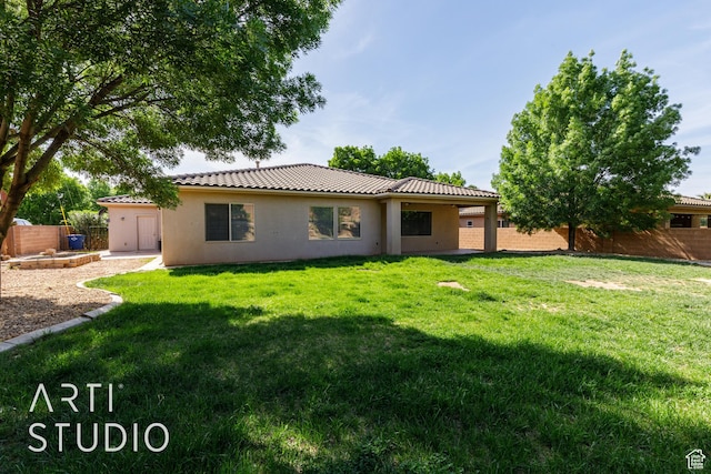 rear view of property with stucco siding, fence, a lawn, and a tiled roof