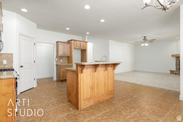 kitchen featuring a kitchen breakfast bar, light carpet, decorative backsplash, and ceiling fan with notable chandelier