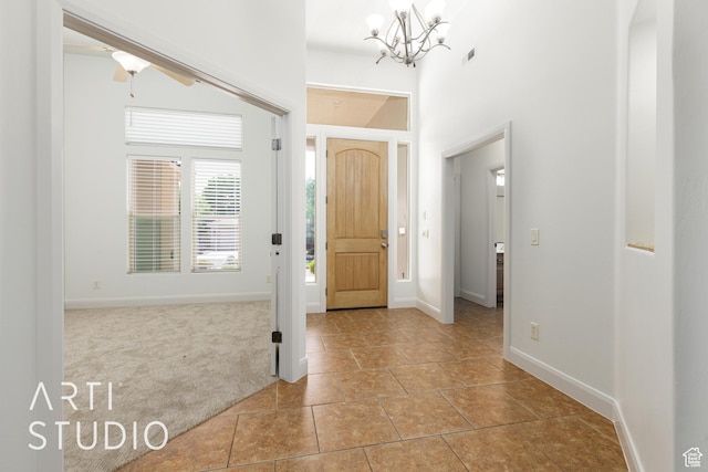 tiled entrance foyer featuring baseboards, visible vents, a notable chandelier, and carpet