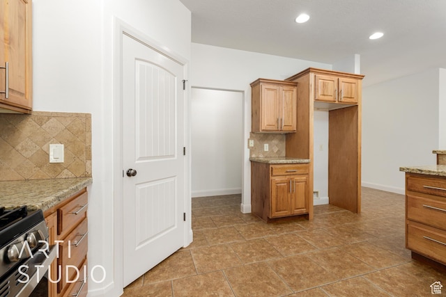 kitchen featuring range with gas stovetop, light stone counters, decorative backsplash, baseboards, and recessed lighting