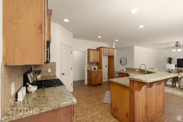 1971 S Great Basin Dr, Washington, UT 84780 - kitchen with stainless steel gas stove, tasteful backsplash, a ceiling fan, a kitchen breakfast bar, and light stone countertops
