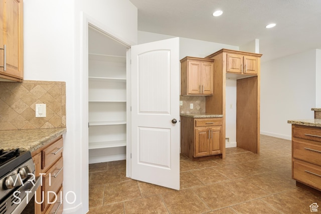 kitchen featuring tasteful backsplash, recessed lighting, light stone counters, light tile patterned floors, and stainless steel range with gas cooktop