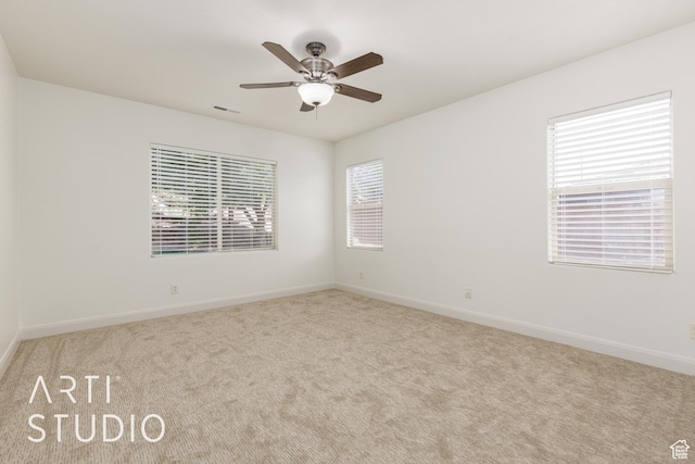carpeted empty room featuring ceiling fan, visible vents, and baseboards