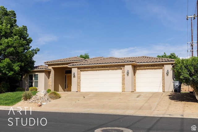 view of front of house featuring stucco siding, driveway, a tiled roof, and an attached garage