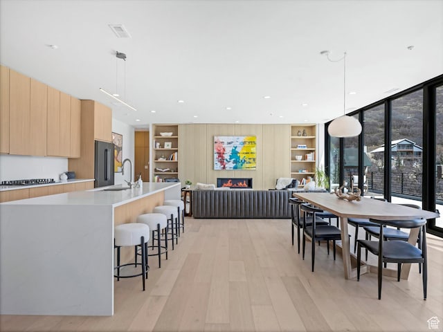 dining room featuring light wood finished floors, built in shelves, and recessed lighting