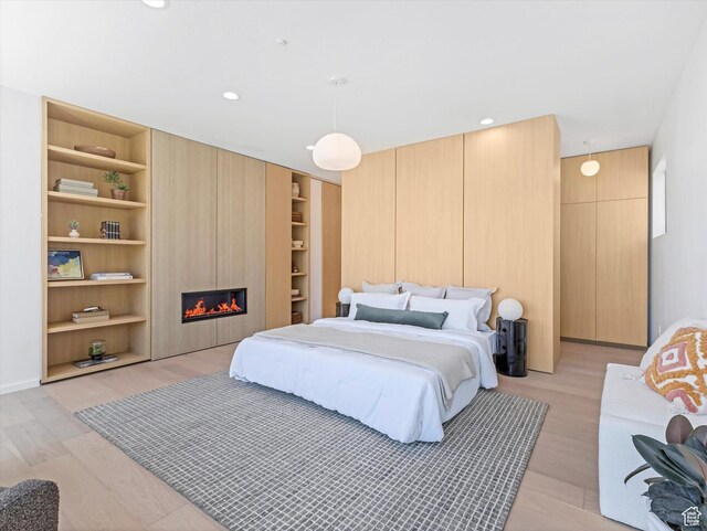 bedroom with light wood-type flooring, a fireplace, and recessed lighting