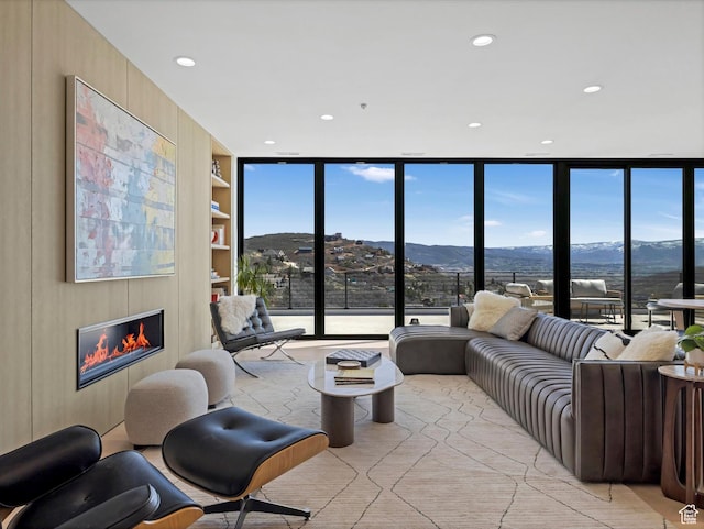 living room with a mountain view, built in shelves, a glass covered fireplace, and recessed lighting