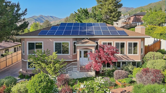 3391 E Brockbank Dr S, Millcreek, UT 84124 - view of front of home with a mountain view, solar panels, stucco siding, and a chimney
