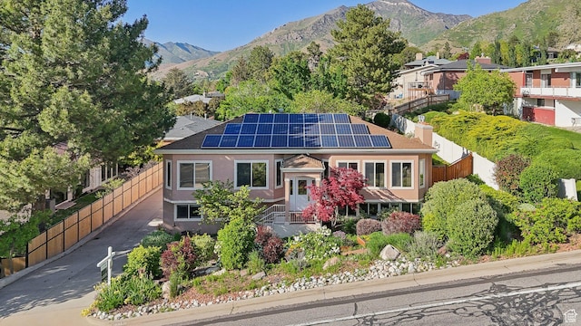 3391 E Brockbank Dr S, Millcreek, UT 84124 - view of front of property with roof mounted solar panels, a mountain view, stucco siding, and a chimney