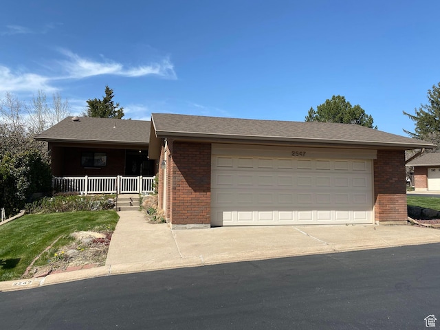 ranch-style home with a garage, brick siding, driveway, and covered porch