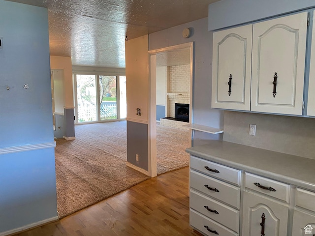 2547 E 1900 N, Layton, UT 84040 - kitchen with white cabinets, wood finished floors, light countertops, a brick fireplace, and open floor plan
