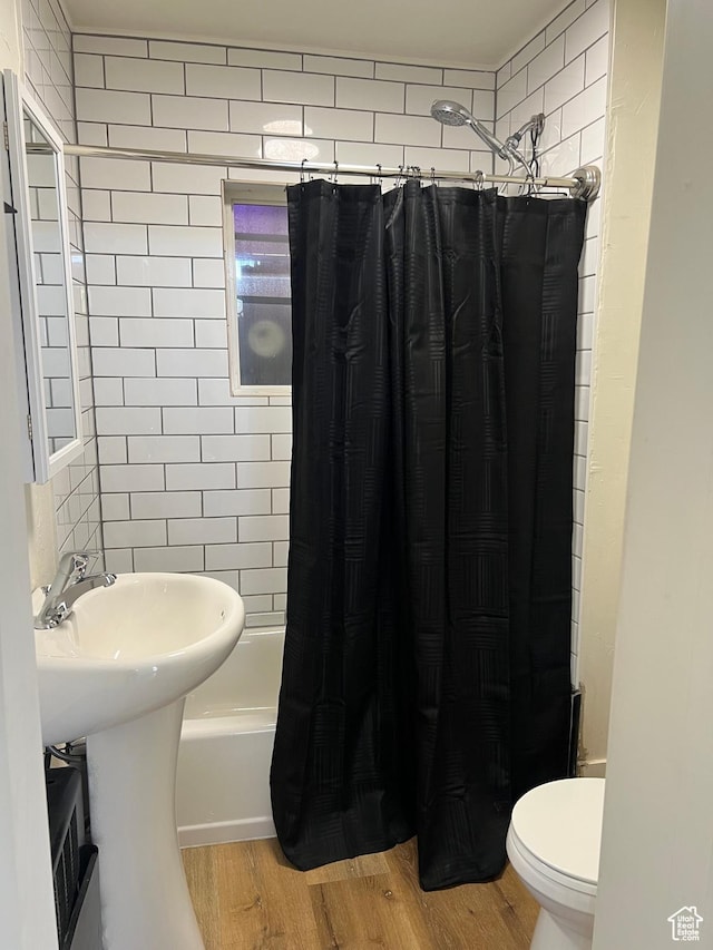 full bath with shower / bath combo, toilet, and wood finished floors