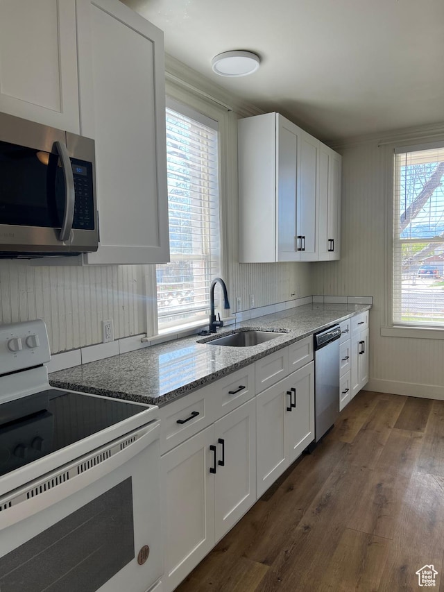 kitchen featuring light stone countertops, white cabinets, dark wood-style flooring, a sink, and stainless steel appliances