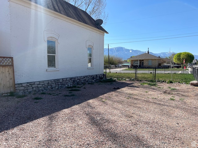 view of side of home featuring a mountain view, fence, and brick siding