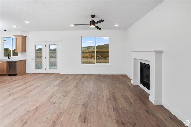 1284 E 1150 S, Garland, UT 84312 - unfurnished living room with light wood-style floors, ceiling fan, a sink, and a glass covered fireplace