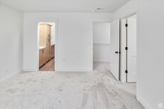 1284 E 1150 S, Garland, UT 84312 - unfurnished bedroom featuring connected bathroom, a spacious closet, visible vents, light carpet, and baseboards