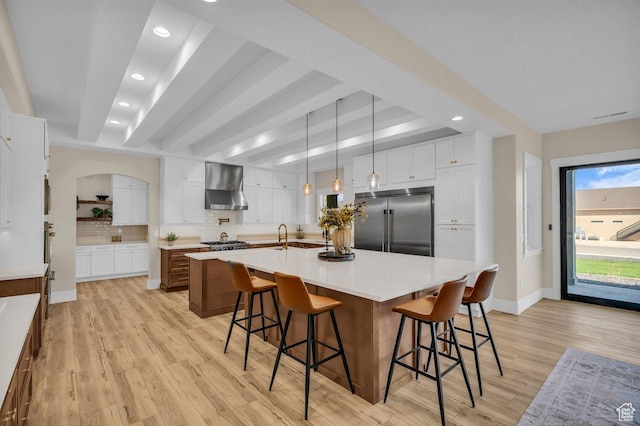 1816 S 920 W, Hurricane, UT 84737 - kitchen featuring wall chimney range hood, light wood finished floors, a spacious island, and stainless steel appliances