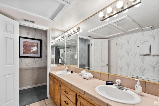 bathroom with a sink, wallpapered walls, double vanity, and visible vents